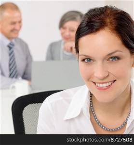 Smiling attractive businesswoman in office closeup with colleagues in background