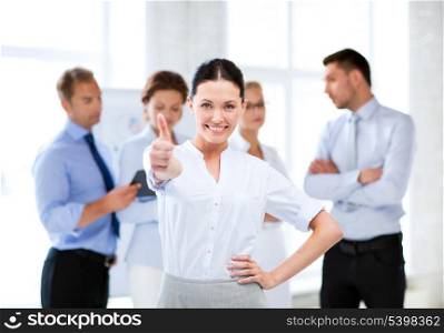 smiling attractive businesswoman in office showing thumbs up