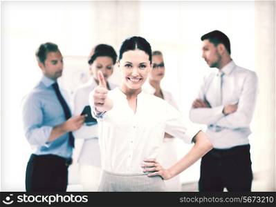smiling attractive businesswoman in office showing thumbs up