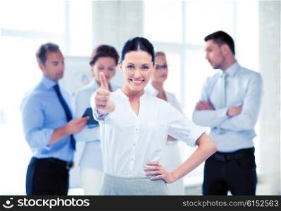 smiling attractive businesswoman in office showing thumbs up. businesswoman in office showing thumbs up