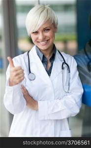 smiling attractive female doctor in front of a glass wall