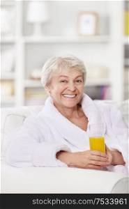 Smiling attractive woman in a bathrobe with a glass of juice