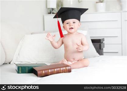 Smiling baby boy in black graduation hat looking in camera. Smiling baby in black graduation hat looking in camera