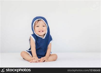 Smiling baby boy wearing blue hooded sitting on bed, Happiness and kids playing concept