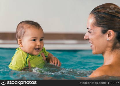 Smiling baby boy with his mother in a swimming pool