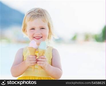Smiling baby eating two ice cream horns