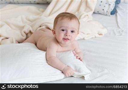 Smiling baby lying on pillows on big bed
