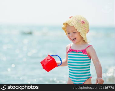 Smiling baby playing with pail on seashore