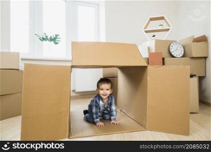 smiling baby toddler inside open cardboard box home
