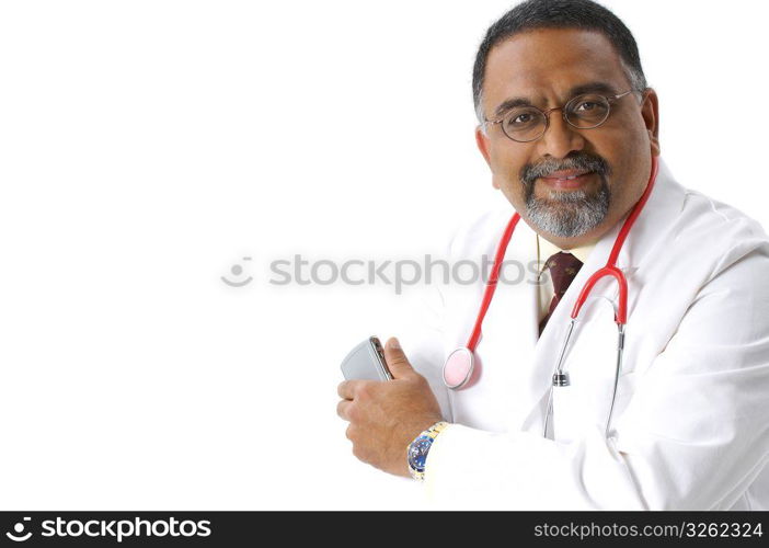 Smiling, bearded Indian doctor in lab coat and stethoscope holding cell phone