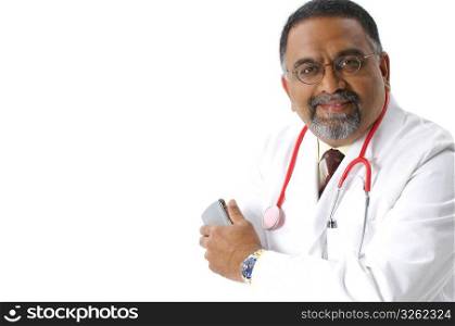 Smiling, bearded Indian doctor in lab coat and stethoscope holding cell phone