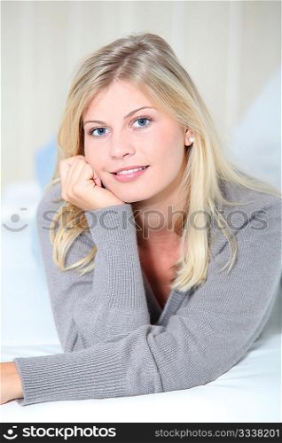 Smiling beautiful blond woman laying on sofa