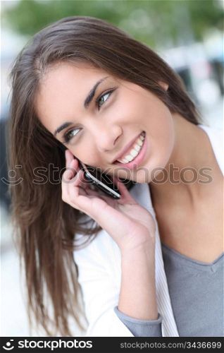 Smiling beautiful girl talking on telephone in town