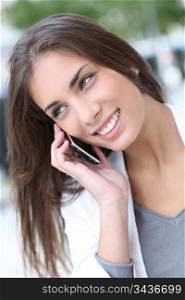 Smiling beautiful girl talking on telephone in town
