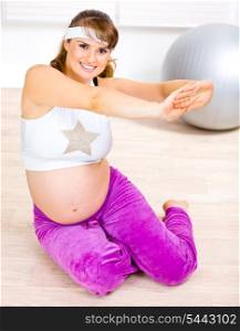 Smiling beautiful pregnant female doing fitness exercises&#xA;