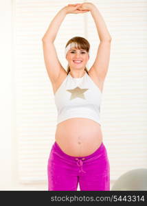 Smiling beautiful pregnant woman doing exercise at home&#xA;