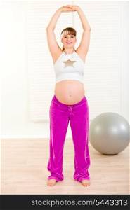Smiling beautiful pregnant woman doing exercise at living room&#xA;