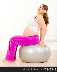 Smiling beautiful pregnant woman doing pilates exercises on gray ball &#xA;