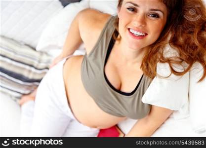 Smiling beautiful pregnant woman relaxing on sofa at home.&#xA;
