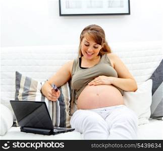 Smiling beautiful pregnant woman using credit card to shop from net&#xA;