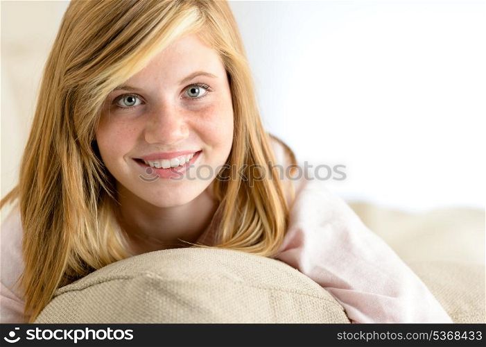 Smiling beautiful teenager girl lying on pillow looking at camera
