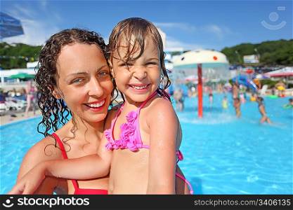 Smiling beautiful woman and little girl bathing in pool of an entertaining complex
