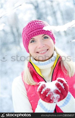 Smiling beautiful woman playing with snow
