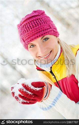 Smiling beautiful woman playing with snow