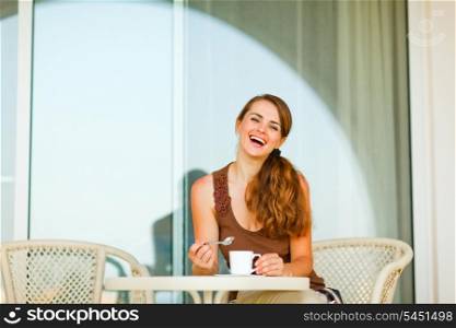 Smiling beautiful woman sitting on terrace and having cup of tea&#xA;