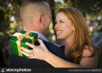Smiling Beautiful Young Woman and Handsome Military Man Exchange a Christmas Gift.