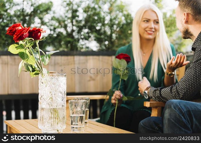 smiling beautiful young woman holding red rose talking his boyfriend