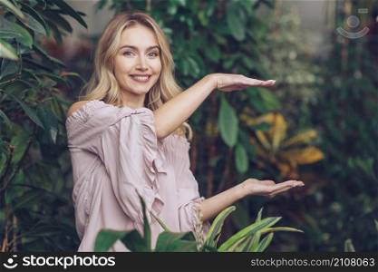 smiling beautiful young woman showing something palms her hands garden