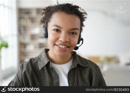 Smiling biracial young female student in headset with microphone learning foreign language online, friendly african american teen girl in headphones looking at camera. Distance education, e-learning.. Biracial girl student in headset learning online, looking at camera. Distance education, elearning