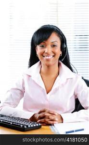 Smiling black customer service and support woman wearing headset at desk