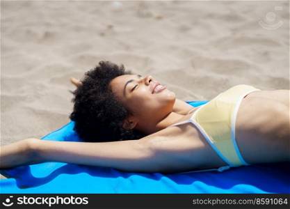 Smiling black woman lying on the sand of a tropical beach sunbathing. African American girl tanning.. Smiling black woman lying on the sand of a tropical beach sunbathing