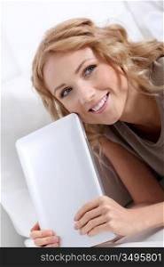Smiling blond woman at home using electronic tablet