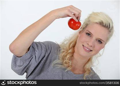 Smiling blond woman holding tomato on white background