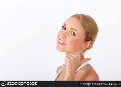 Smiling blond woman showing thumb up on white background