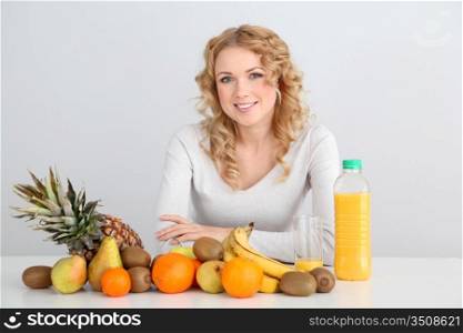 Smiling blond woman sitting with fruits on table