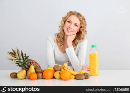 Smiling blond woman sitting with fruits on table