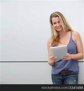 Smiling blond woman using electronic tablet on grey background
