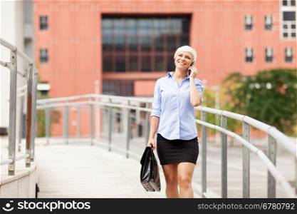 Smiling blonde businesswoman is walking while phoning and smiling