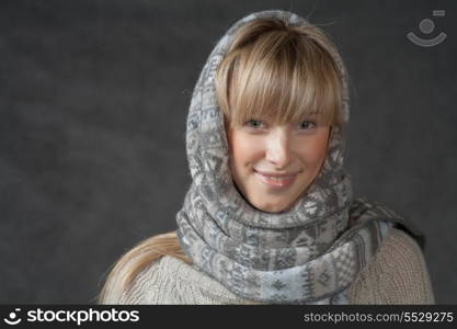 Smiling blonde in studio front view. Portrait of woman on dark background wearing woolen accessories