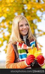 Smiling blonde teen girl autumn forest holding dry leaves