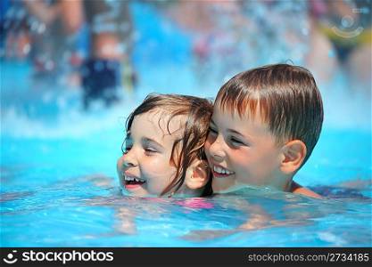 Smiling boy and little girl swimming in pool in aquapark