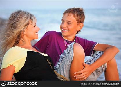 smiling boy and young woman on beach in evening, Looking against each other