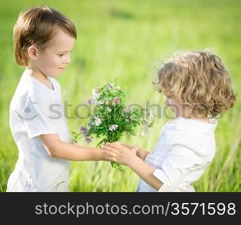Smiling boy giving bouquet of spring flowers to happy girl