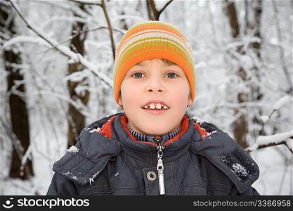 smiling boy in cap in wood in winter