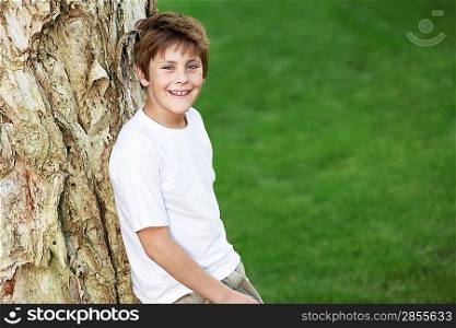 Smiling Boy Leaning Against Tree