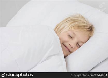 Smiling boy sleep in bed. Cheerful smiling blond boy sleep in white bed